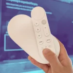 Google TV Streamer and Remote held in front of a wall-mounted TV